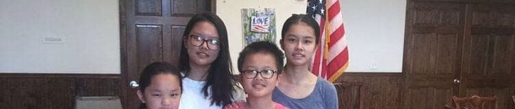 Four students in the school hall beside the American flag