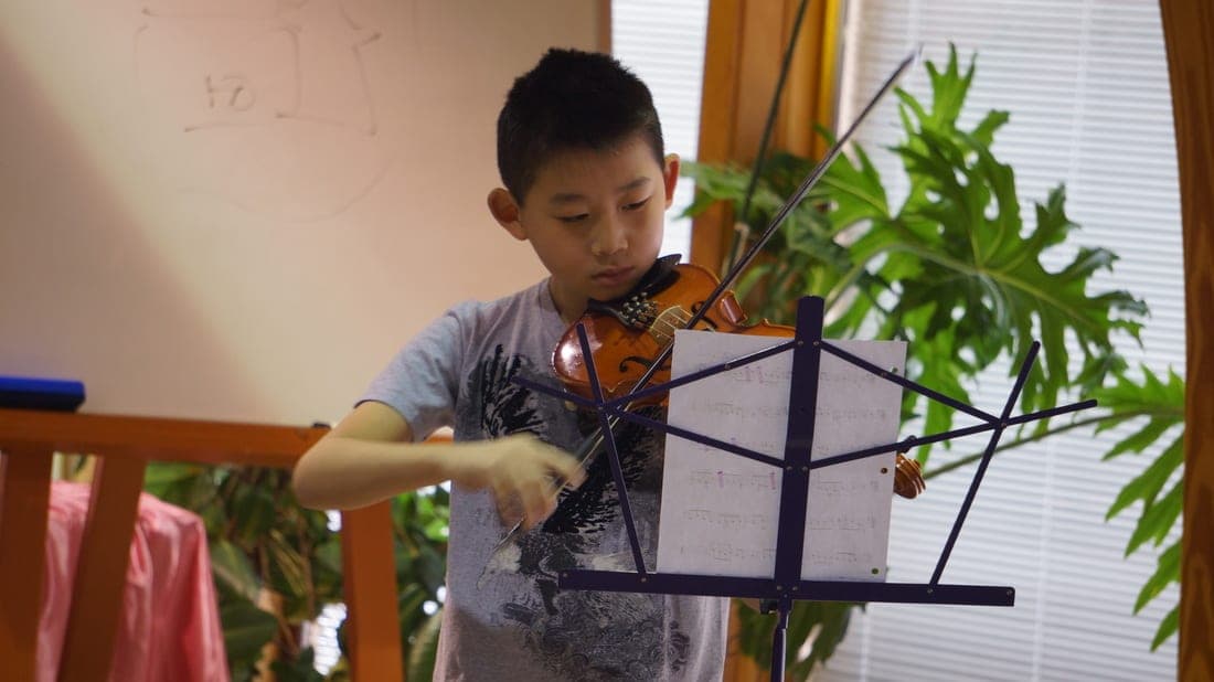A student playing the violin at a school concert
