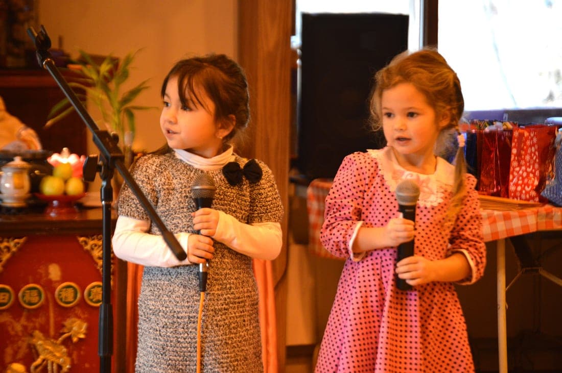 Two young students singing into microphones at a school celebration